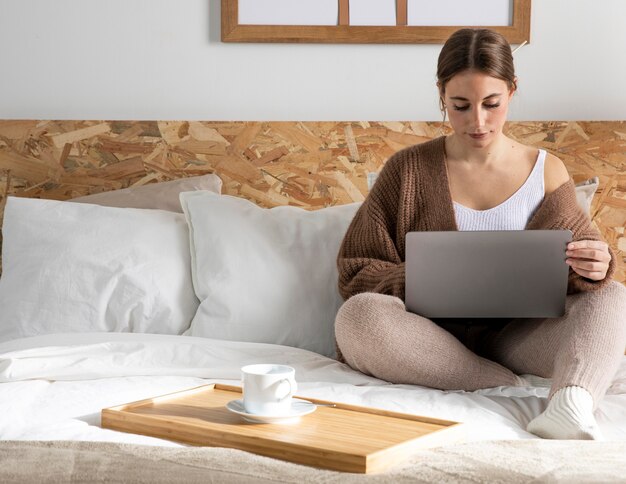 Foto gratuita mujer de tiro completo que trabaja en el dormitorio