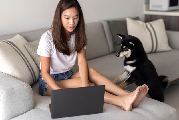 Mujer de tiro completo que trabaja en el sofá con lindo perro