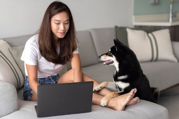 Mujer de tiro completo que trabaja en el sofá con el perro