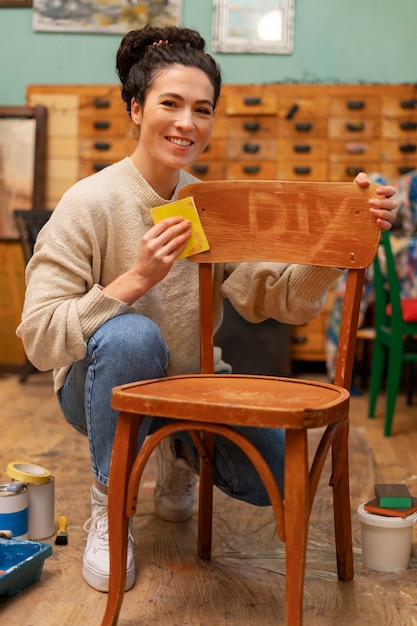 Mujer de tiro completo restaurando silla de madera.