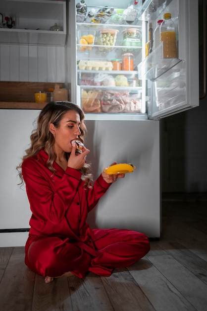 Mujer de tiro completo revisando el refrigerador por la noche