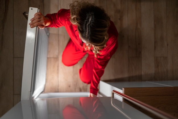 Foto gratuita mujer de tiro completo revisando el refrigerador por la noche