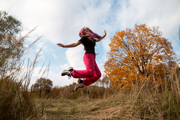 Mujer de tiro completo saltando en la naturaleza