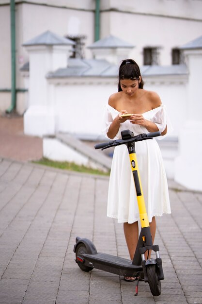 Mujer de tiro completo con scooter al aire libre
