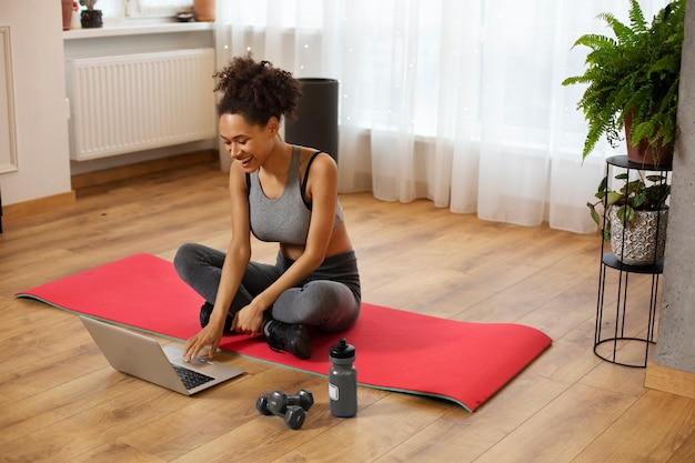 Mujer de tiro completo sentada en la estera de yoga