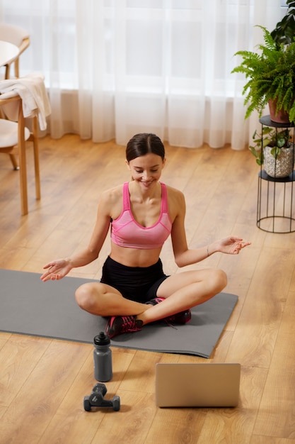 Mujer de tiro completo sentada en la estera de yoga