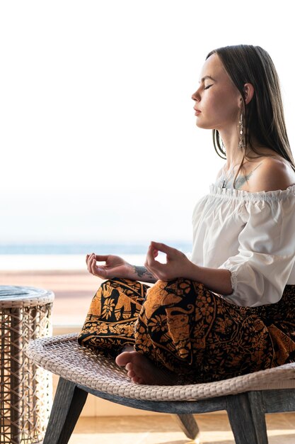 Mujer de tiro completo en silla meditando