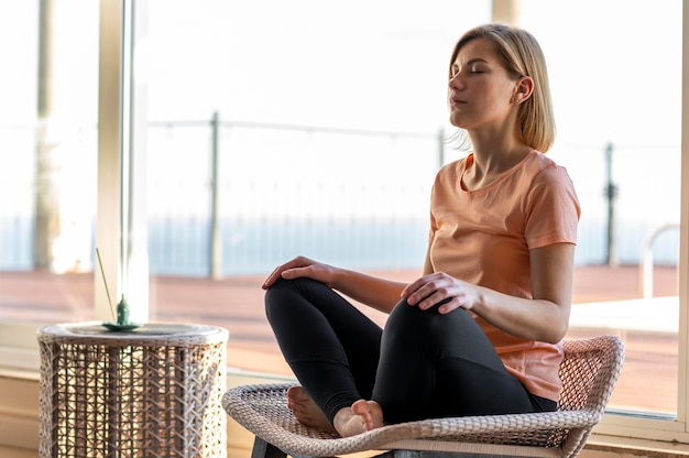 Mujer de tiro completo en silla meditando