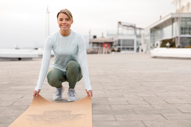 Foto gratuita mujer de tiro completo sosteniendo estera de yoga