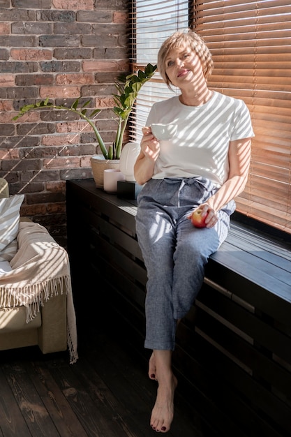 Mujer de tiro completo sosteniendo la taza y la manzana