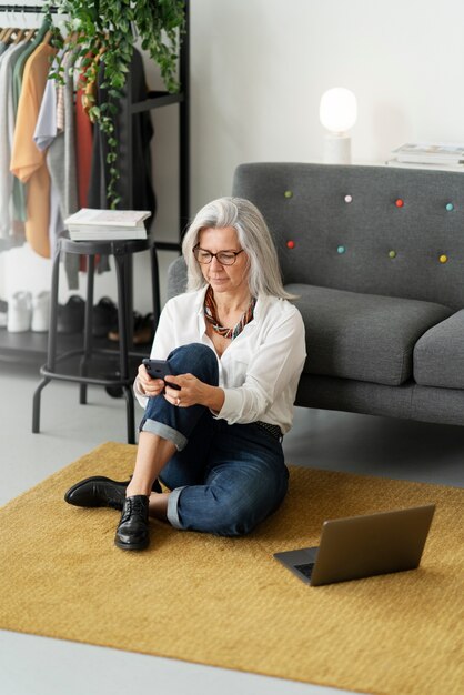 Mujer de tiro completo con teléfono inteligente en el piso