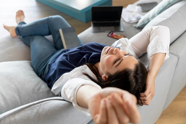 Mujer de tiro completo tendido en el sofá