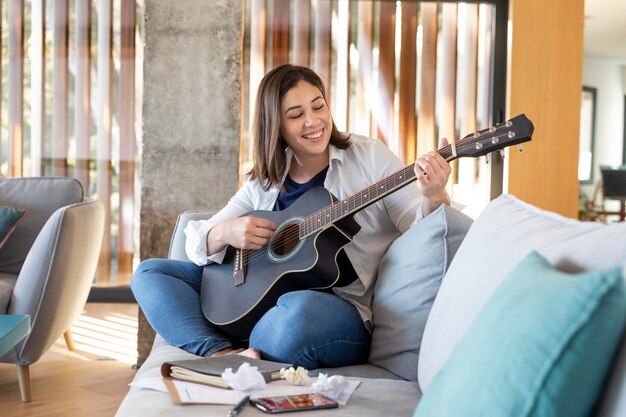 Mujer de tiro completo tocando la guitarra