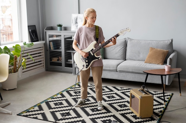 Mujer de tiro completo tocando la guitarra