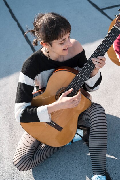 Mujer de tiro completo tocando la guitarra