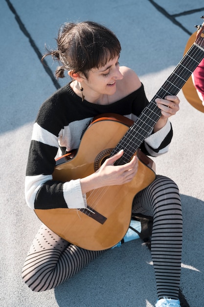 Mujer de tiro completo tocando la guitarra