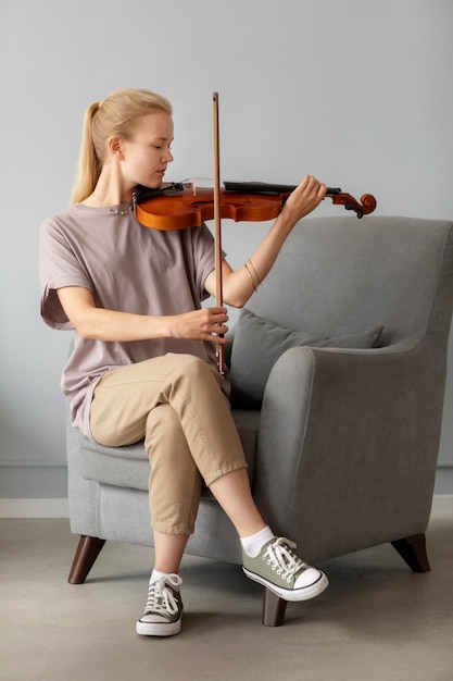 Mujer de tiro completo tocando el violín