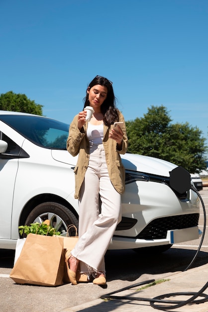 Mujer de tiro completo tomando café junto al auto