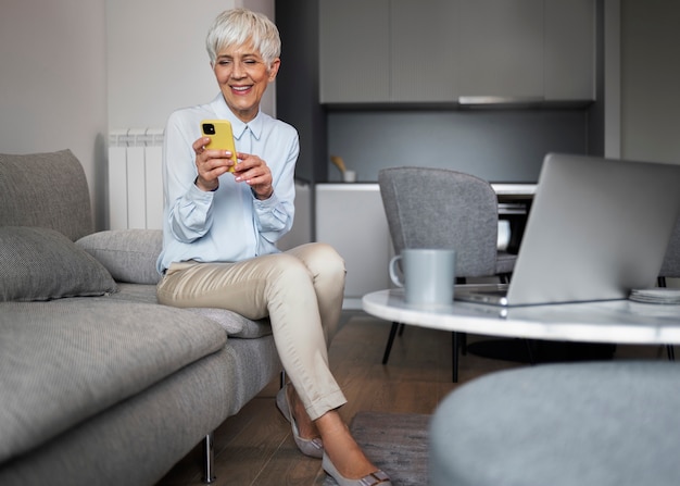 Foto gratuita mujer de tiro completo tomando un descanso con teléfono inteligente