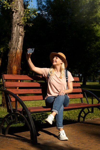Mujer de tiro completo tomando selfie en banco