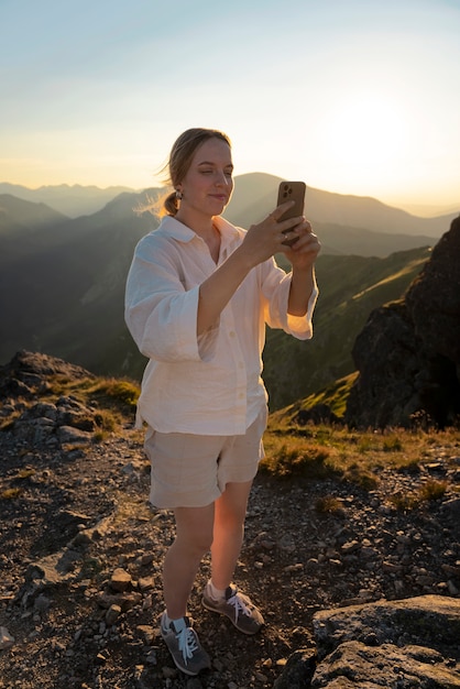 Mujer de tiro completo tomando selfie en la montaña