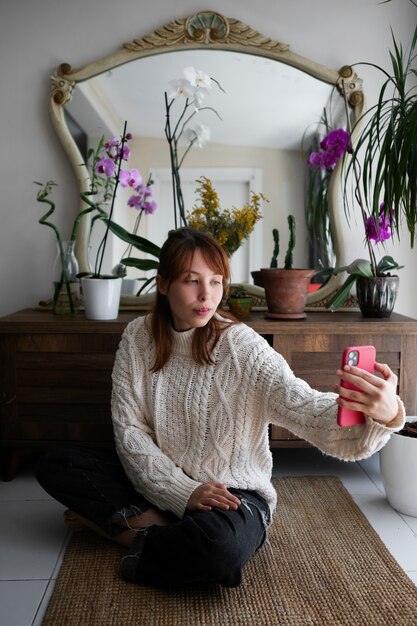 Mujer de tiro completo tomando selfie con plantas