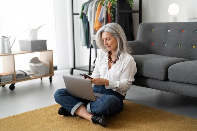 Mujer de tiro completo trabajando en la computadora portátil en el piso