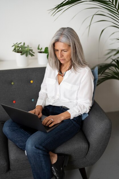 Mujer de tiro completo trabajando en la computadora portátil en el sofá