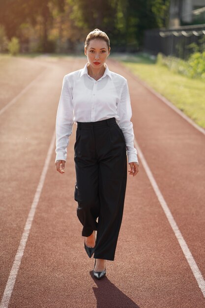 Mujer de tiro completo con traje en la pista de atletismo