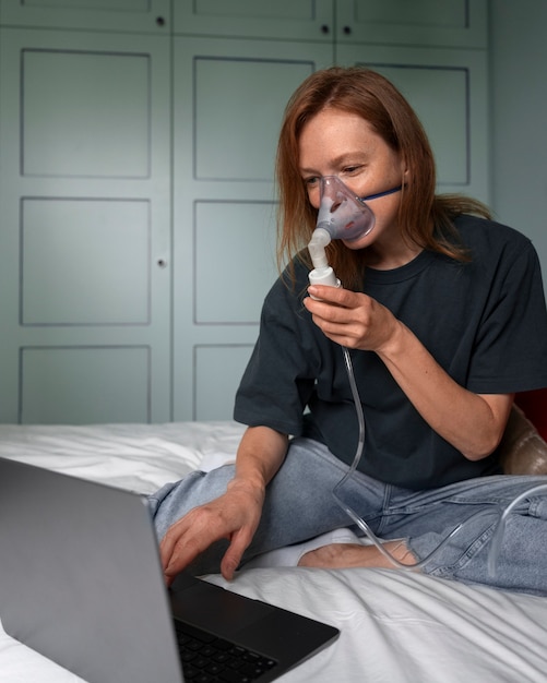 Mujer de tiro completo usando nebulizador en casa