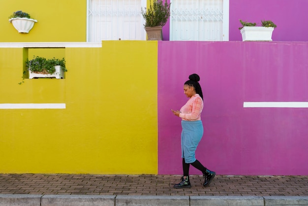 Mujer de tiro completo usando un teléfono inteligente al aire libre