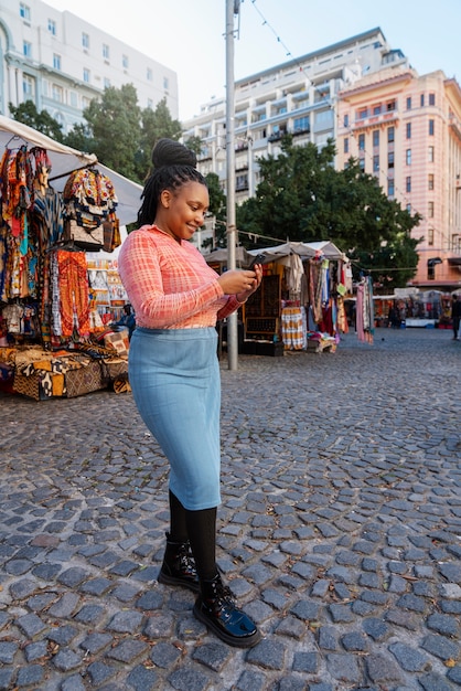 Foto gratuita mujer de tiro completo usando un teléfono inteligente al aire libre