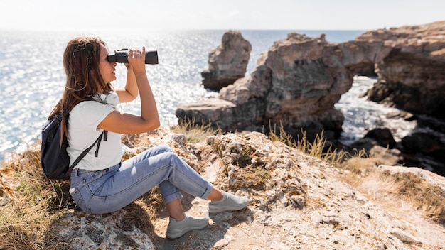Mujer de tiro largo con binoculares con espacio de copia