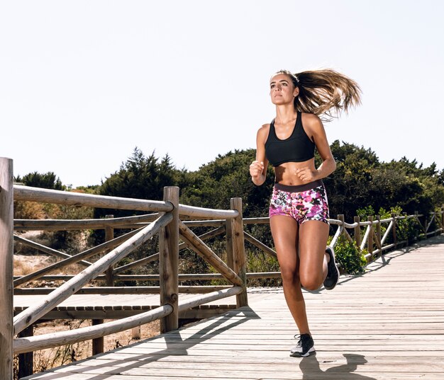 Mujer de tiro largo corriendo en el muelle