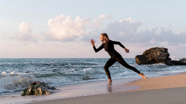 Mujer de tiro largo corriendo en la playa