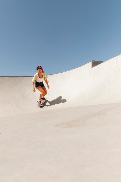 Mujer de tiro largo con patineta al aire libre