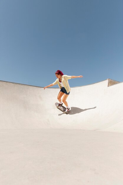 Mujer de tiro largo en patineta fuera