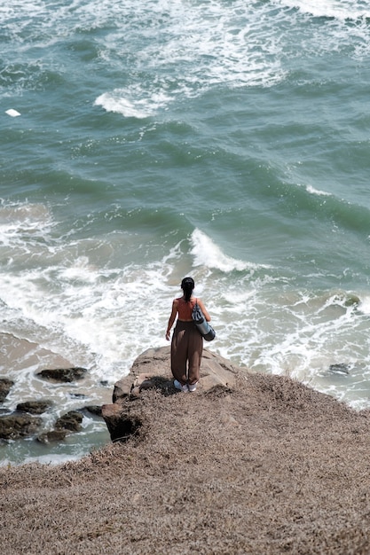 Mujer de tiro largo en la playa con estera de yoga