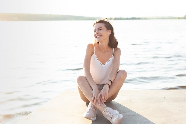 Mujer de tiro largo posando mientras está sentado en un muelle