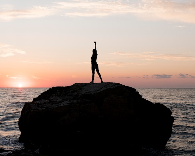 Mujer de tiro largo en ropa deportiva disfrutando de la puesta de sol