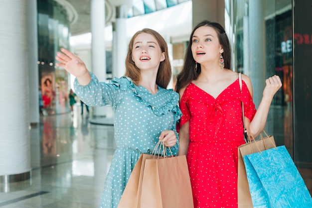 Foto gratuita mujer de tiro medio apuntando lejos en el centro comercial