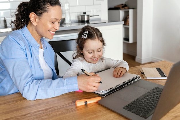 Mujer de tiro medio ayudando a niña con la tarea