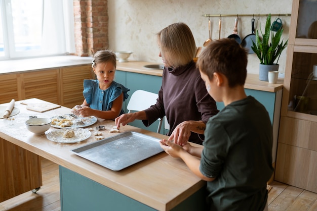 Mujer de tiro medio ayudando a los niños a cocinar