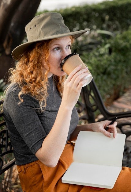 Mujer de tiro medio en un banco tomando café