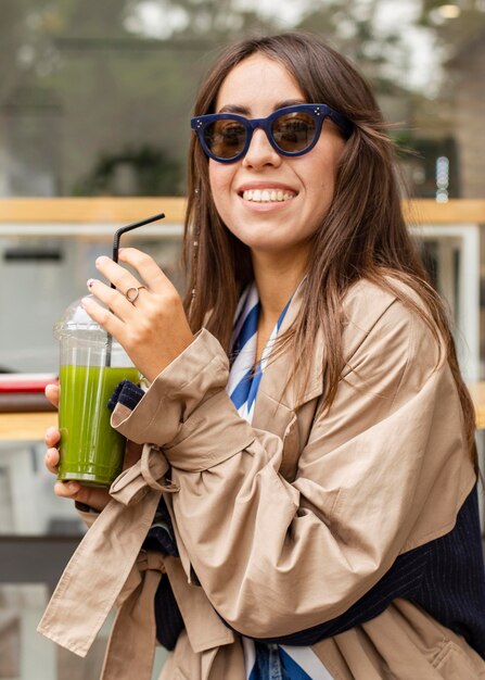 Mujer de tiro medio bebiendo batido verde