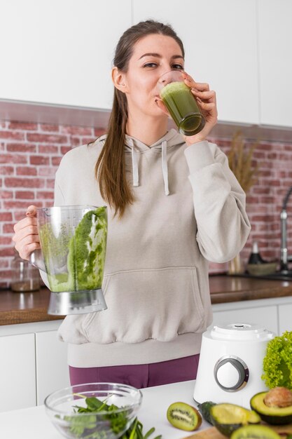 Mujer de tiro medio bebiendo batido