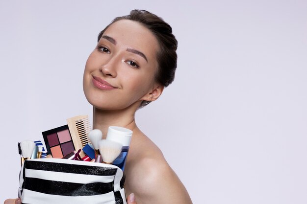 Mujer de tiro medio con bolsa de maquillaje