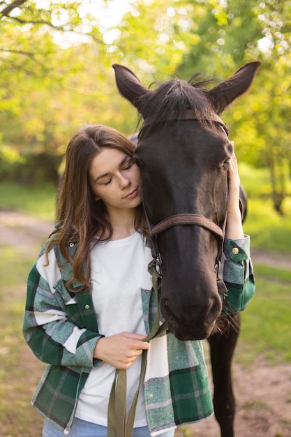 Mujer de tiro medio y caballo en la naturaleza