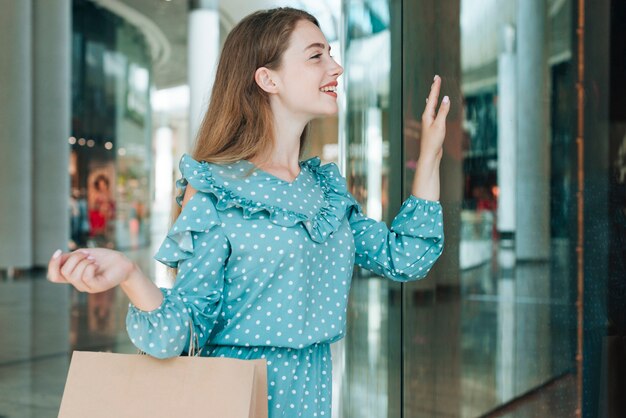 Mujer de tiro medio en el centro comercial saludando