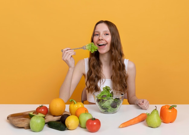 Mujer de tiro medio comiendo lechuga